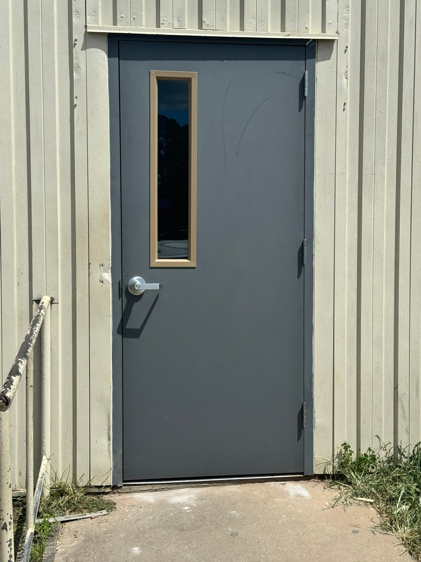 Gray hollow metal door with a narrow vision lite and lever handle