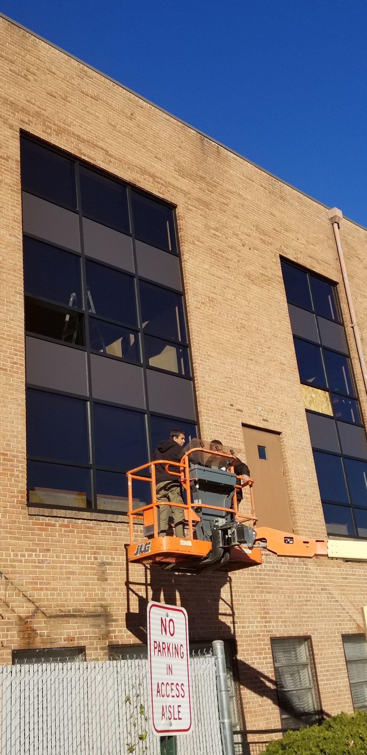 Boom lift used to replace insulated glass windows on a brick office building