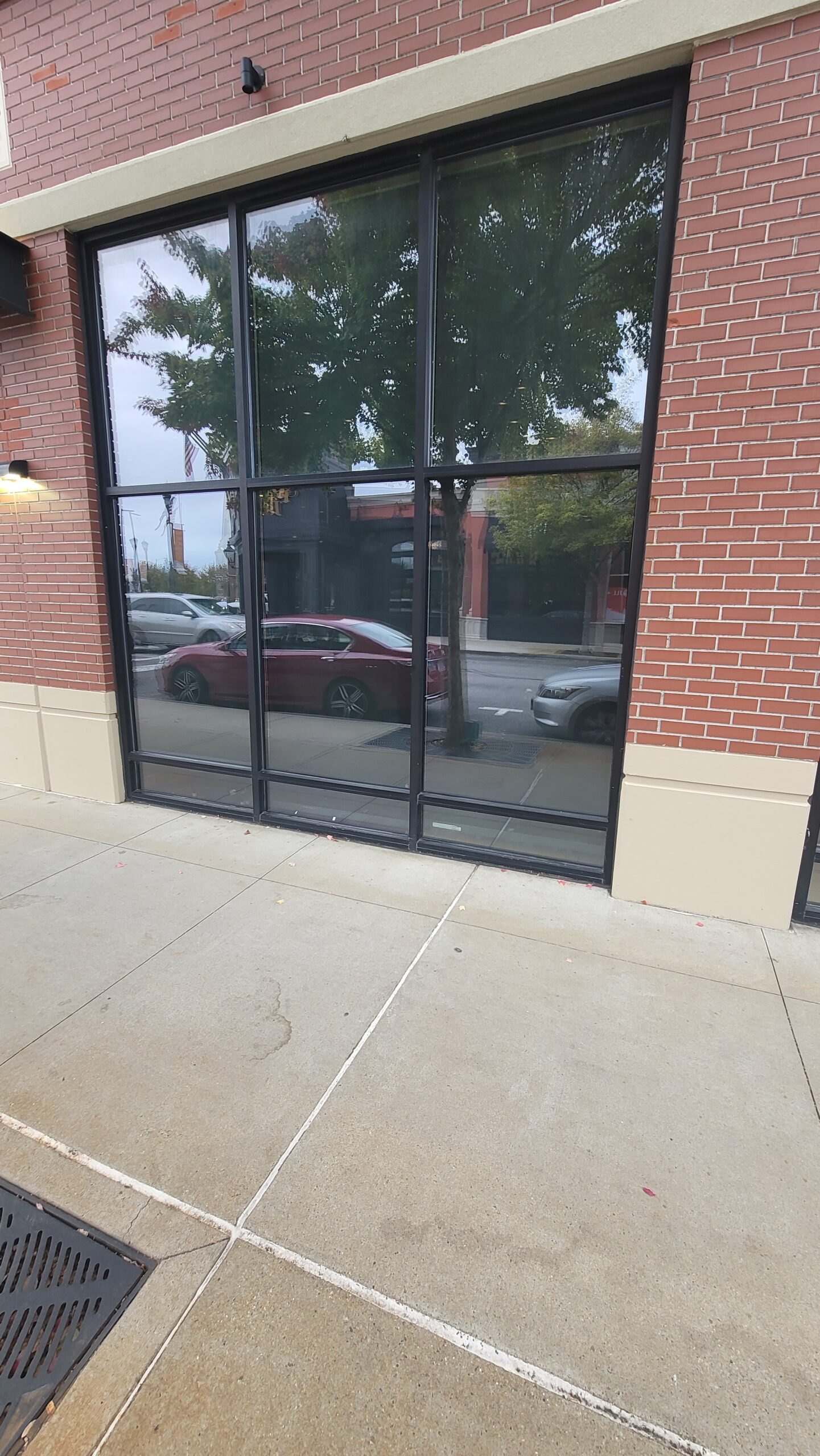 Large black-framed storefront window glass on a brick commercial building
